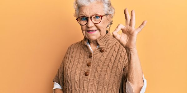 Senior grey-haired woman wearing casual clothes and glasses smiling positive doing ok sign with hand and fingers. successful expression.