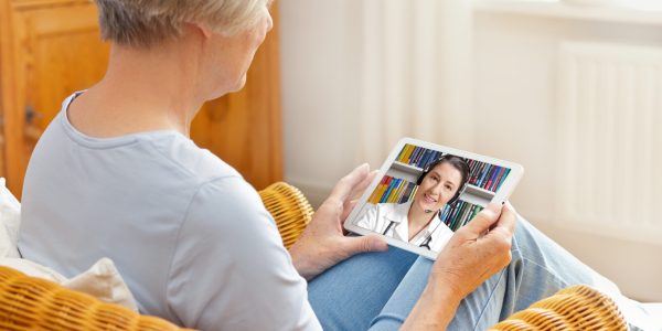 telemedicine concept, old woman with tablet pc during an online consultation with her doctor in her living room