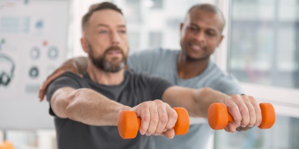 Sports,Equipment.,Selective,Focus,Of,Orange,Dumbbells,Being,Held,By