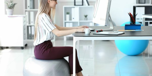 Young,Businesswoman,Sitting,On,Fitball,While,Working,In,Office