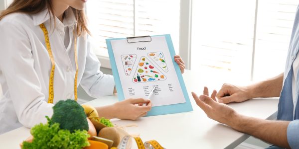 Young,Nutritionist,Consulting,Patient,At,Table,In,Clinic,,Closeup