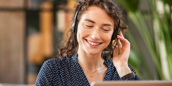 Happy,Young,Woman,Working,On,Laptop,While,Talking,To,Customer