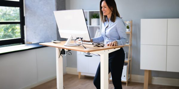 Woman,Using,Adjustable,Height,Standing,Desk,In,Office,For,Good