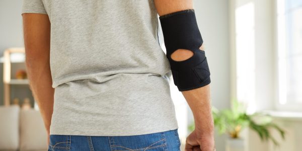 Young,Man,Wearing,An,Adjustable,Black,Neoprene,Orthopedic,Elbow,Support