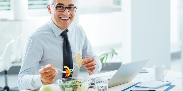 Smiling,Businessman,Sitting,At,Office,Desk,And,Having,A,Lunch