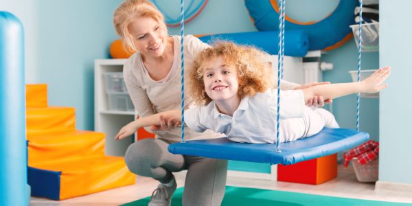 Woman,Helping,A,Smiling,Boy,To,Exercise,On,A,Therapy